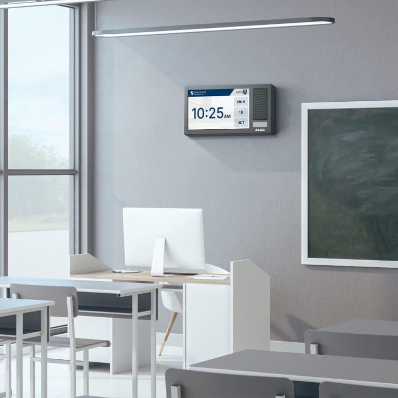 Algo IP 8410 Display Speaker mounted on a wall in a school classroom displaying the time.