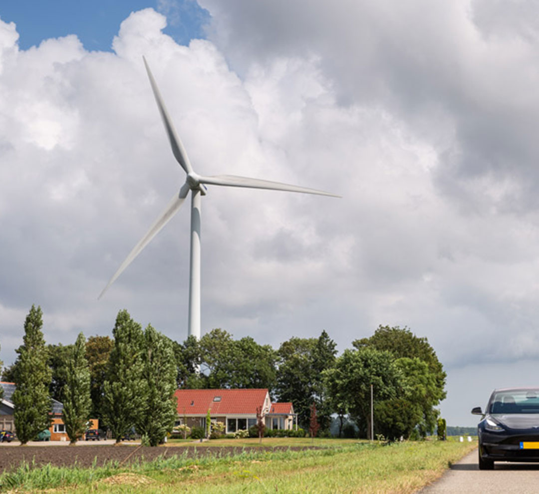 Electric car standing next to a windmill