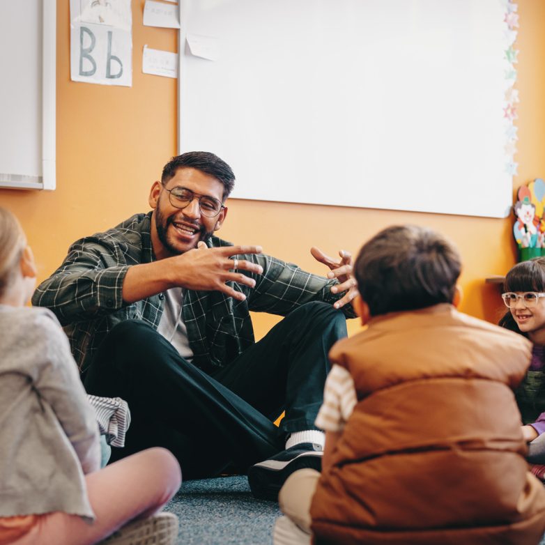 Image of teacher and students sitting in a circle and smiling