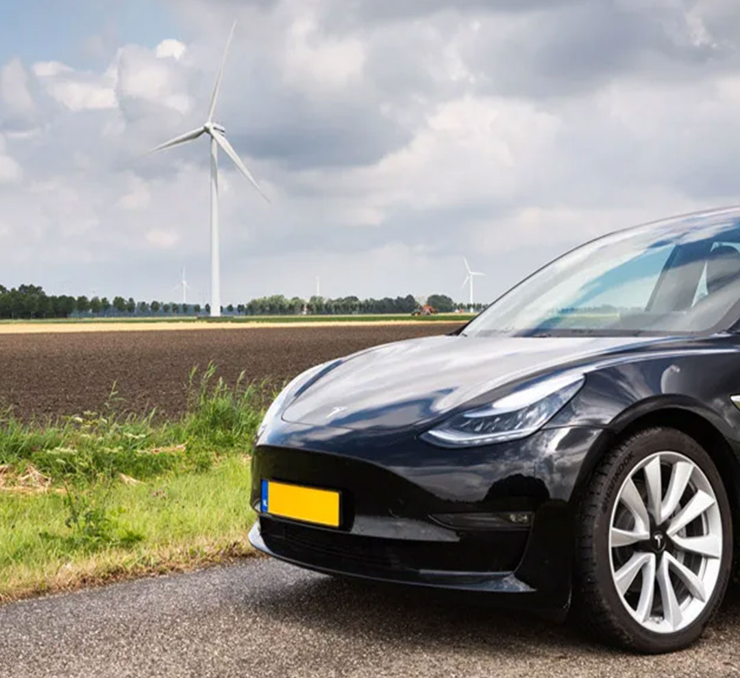 electric car standing on the road with a windmill next to it
