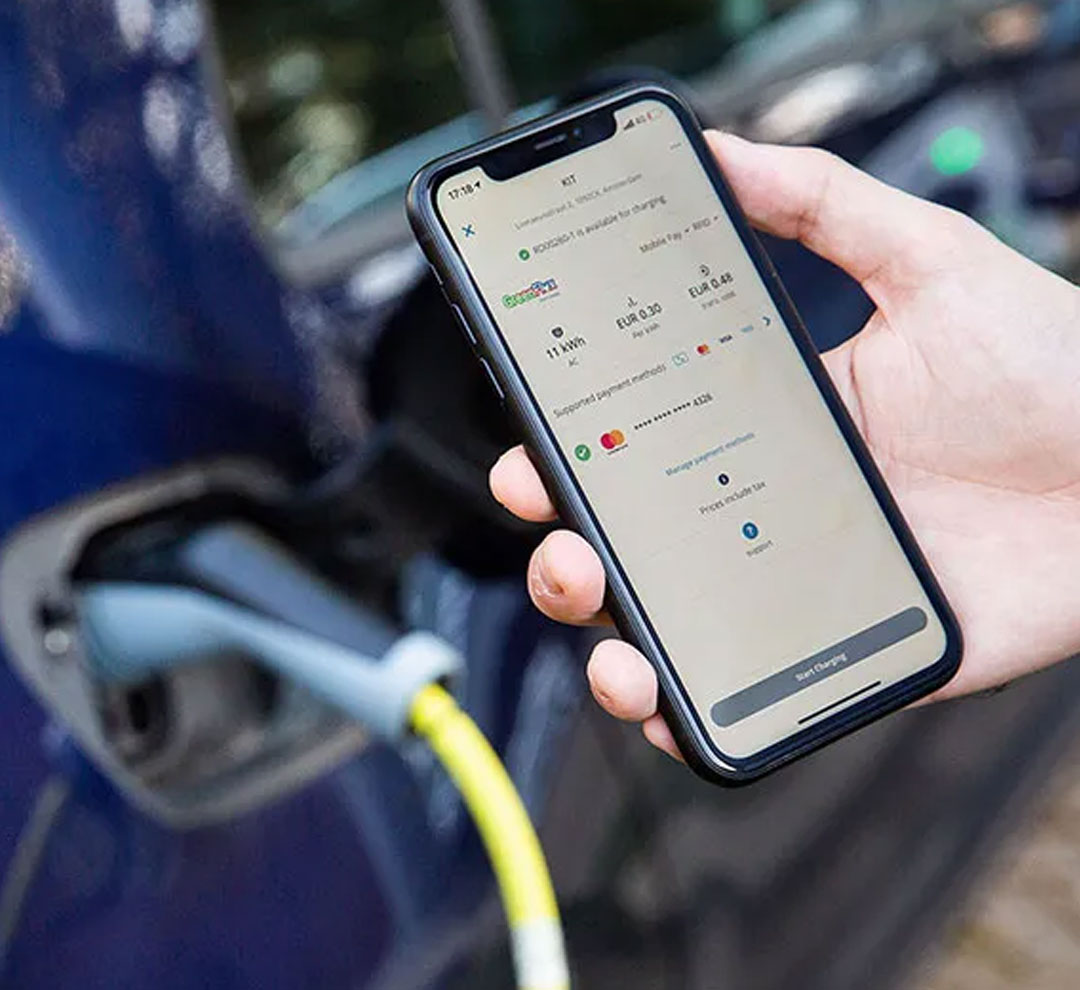 Man holding Charge Assist App next to an electric vehicle