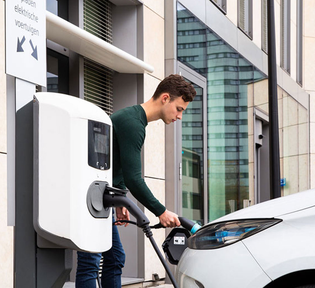 Man charging its electric vehicle at a charging point