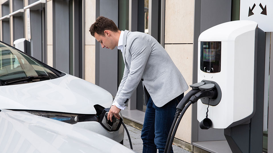 Man charging its electric car at a charging station