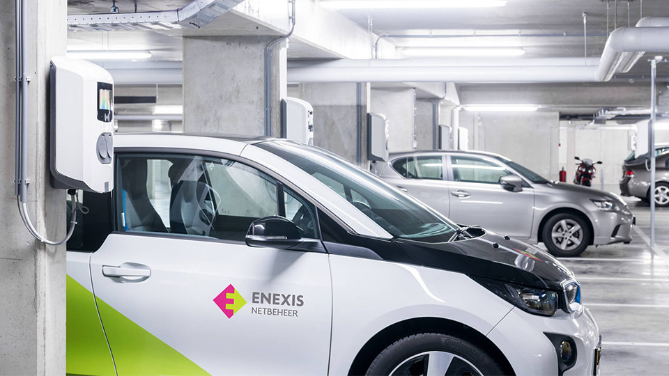 row of electric cars plugged into charge stations in a parking garage