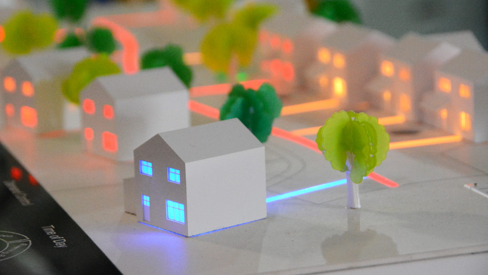 small scale model of residential neighborhood with different colored lights depicting electricity flow