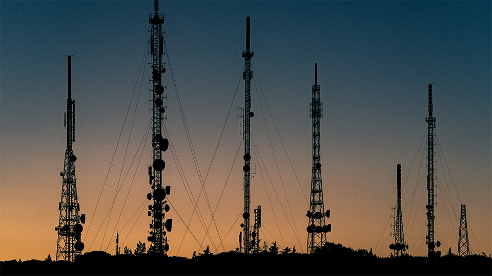 Network and communication towers with sunset in background